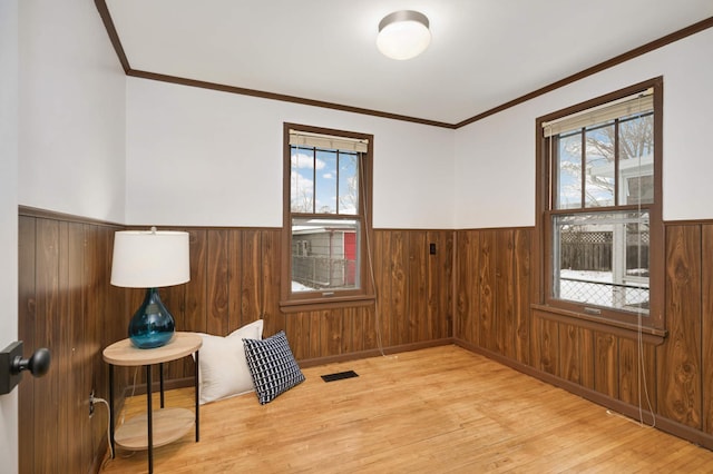 sitting room featuring a healthy amount of sunlight, light hardwood / wood-style flooring, and wood walls