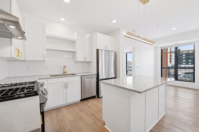 kitchen featuring sink, white cabinets, hanging light fixtures, exhaust hood, and stainless steel appliances