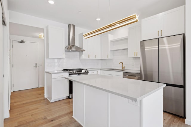 kitchen featuring white cabinetry, appliances with stainless steel finishes, a center island, and wall chimney range hood