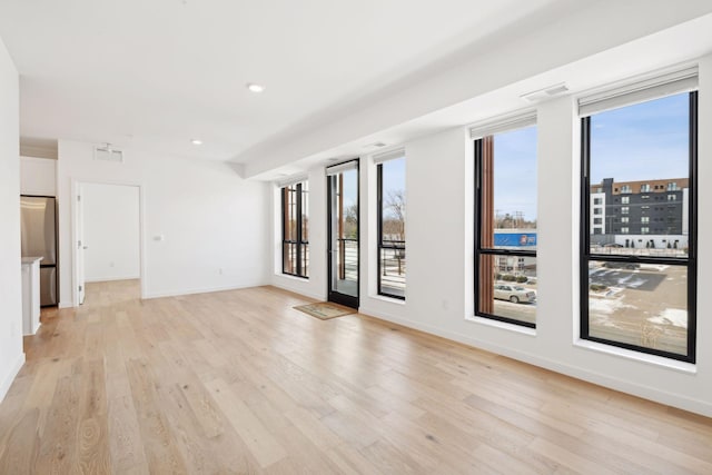 empty room with a wealth of natural light and light hardwood / wood-style floors