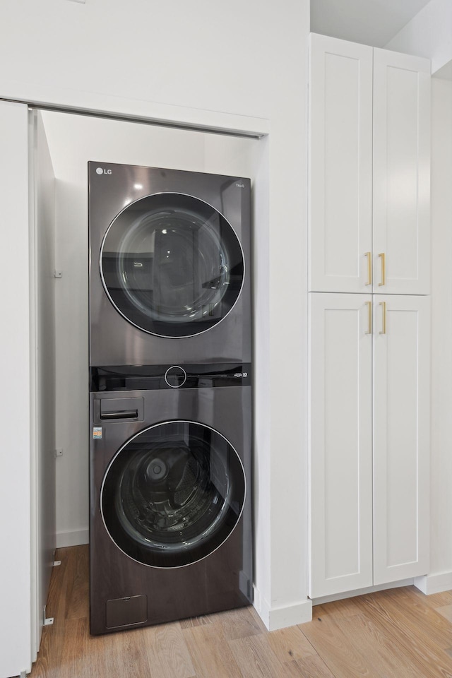 clothes washing area featuring stacked washer and clothes dryer and light wood-type flooring