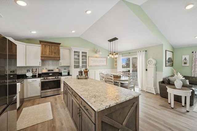 kitchen featuring lofted ceiling, appliances with stainless steel finishes, decorative light fixtures, and white cabinets