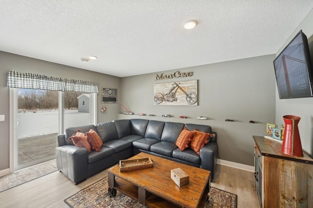 living area with light wood-type flooring, a textured ceiling, and baseboards