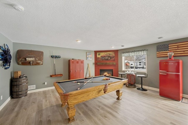 rec room with pool table, wood finished floors, visible vents, baseboards, and a glass covered fireplace