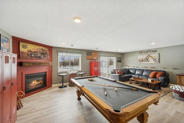 game room featuring a textured ceiling, pool table, a fireplace, and wood finished floors