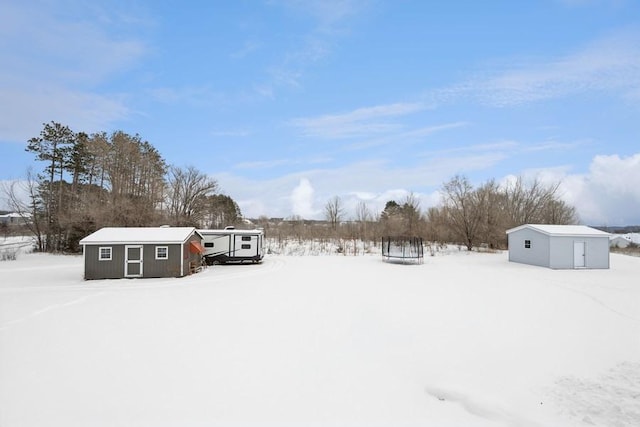 snowy yard with an outdoor structure and a shed