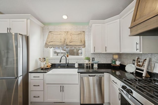 kitchen with premium range hood, a sink, white cabinets, appliances with stainless steel finishes, and decorative backsplash