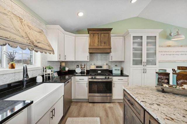 kitchen with lofted ceiling, stainless steel appliances, and white cabinetry