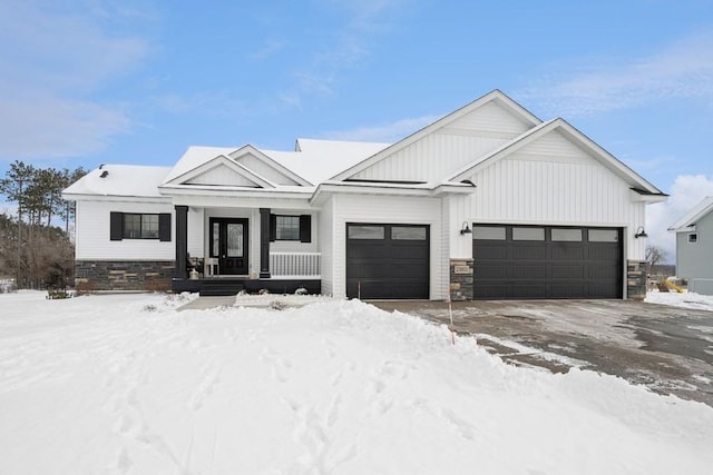 modern farmhouse with board and batten siding, stone siding, and an attached garage