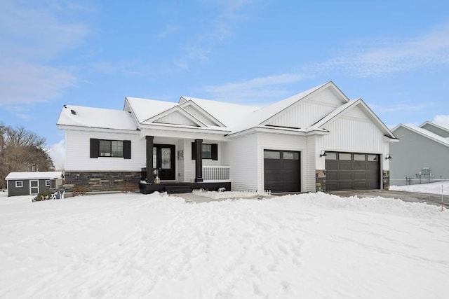 view of front of property featuring stone siding, covered porch, board and batten siding, and an attached garage