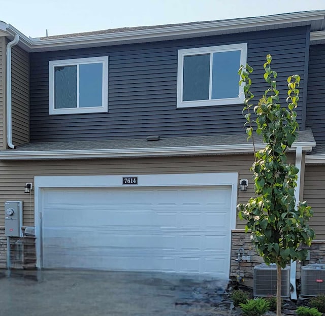 view of side of home with a garage and central AC unit