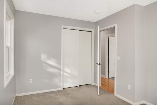 unfurnished bedroom featuring light colored carpet and a closet