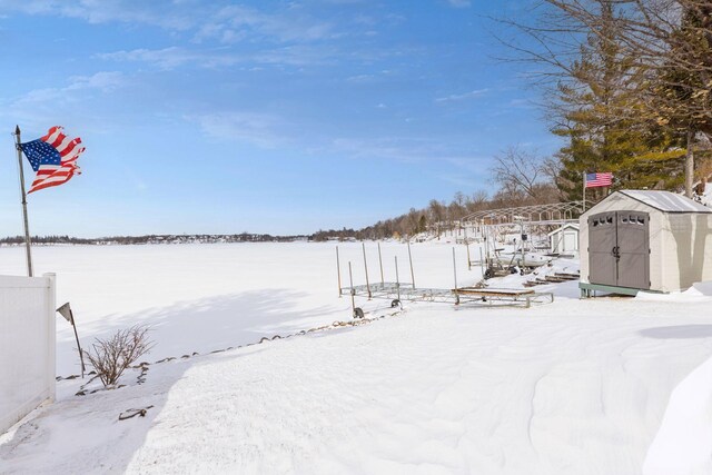 yard layered in snow featuring a storage shed and an outdoor structure