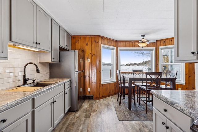 kitchen featuring wood finished floors, wood walls, a sink, and tasteful backsplash