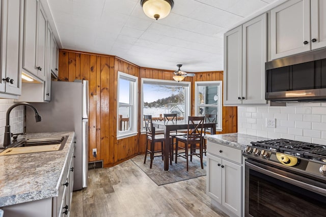 kitchen featuring tasteful backsplash, visible vents, light wood-style flooring, appliances with stainless steel finishes, and a sink