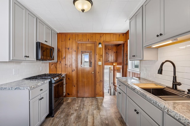 kitchen featuring wood finished floors, stainless steel appliances, light countertops, gray cabinetry, and a sink