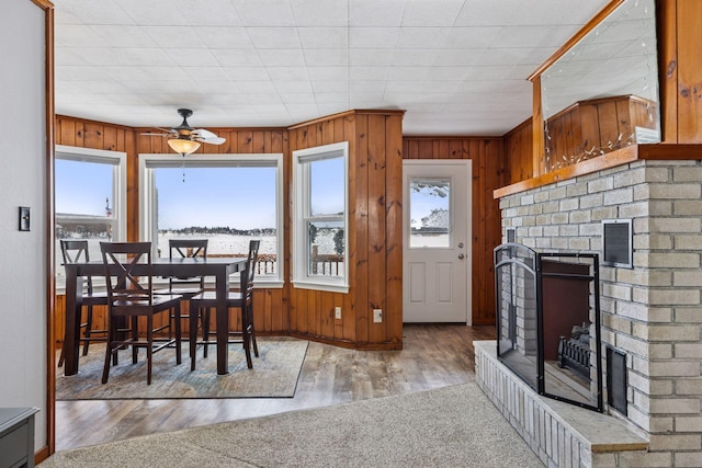 dining area featuring a brick fireplace, visible vents, wood finished floors, and wood walls