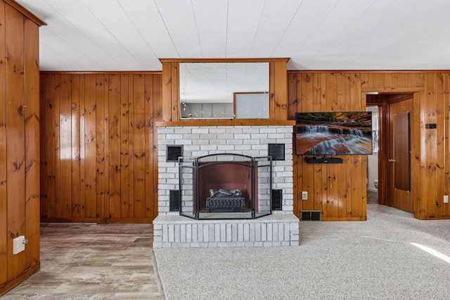 carpeted living area featuring visible vents, a fireplace, and wooden walls