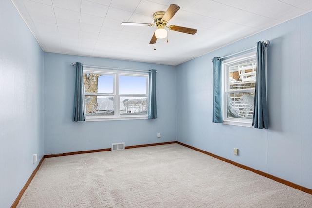 spare room with a healthy amount of sunlight, carpet, visible vents, and ceiling fan