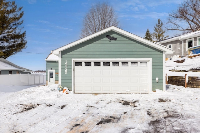 snow covered garage with fence