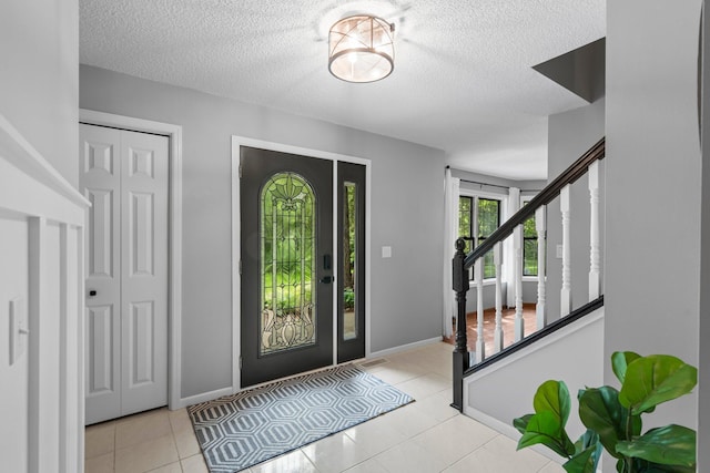 17130 Uplander Cir NW, Andover, MN 55304 - foyer entrance with a textured ceiling, stairs, light tile patterned flooring, and baseboards