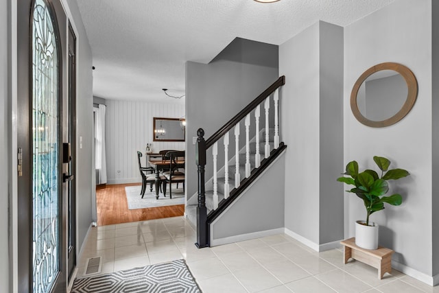 17130 Uplander Cir NW, Andover, MN 55304 - foyer entrance with light tile patterned flooring, a textured ceiling, baseboards, and stairway