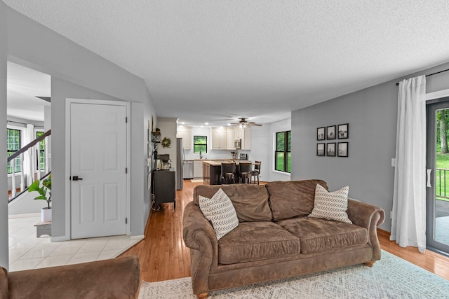 17130 Uplander Cir NW, Andover, MN 55304 - living room featuring healthy amount of natural light, stairway, light wood-type flooring, a textured ceiling, and ceiling fan