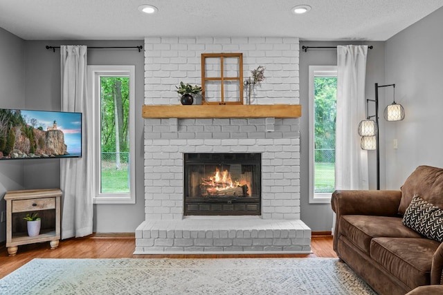17130 Uplander Cir NW, Andover, MN 55304 - living area featuring a fireplace, wood finished floors, baseboards, and a textured ceiling