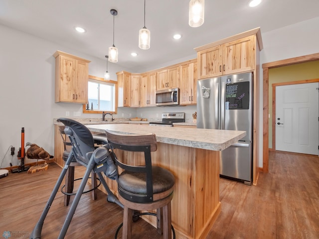 kitchen with light brown cabinetry, sink, light hardwood / wood-style flooring, appliances with stainless steel finishes, and pendant lighting