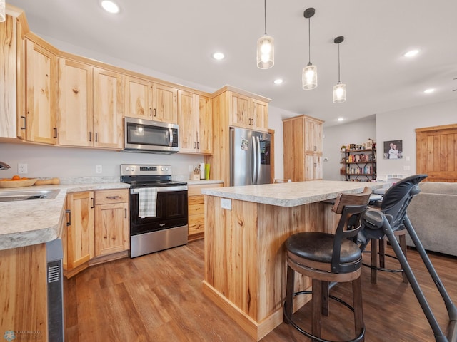 kitchen with appliances with stainless steel finishes, light wood-type flooring, pendant lighting, and light brown cabinetry