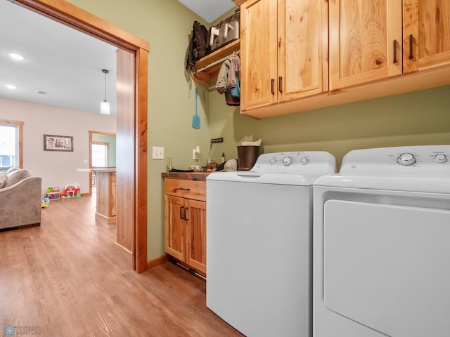 laundry area featuring cabinets, light hardwood / wood-style floors, and washing machine and dryer