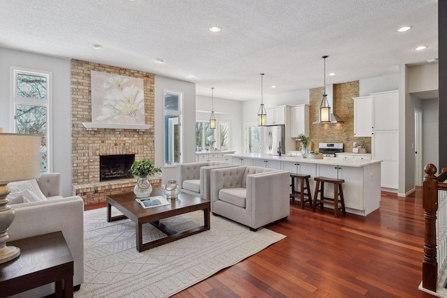 living room featuring dark wood-type flooring, recessed lighting, a fireplace, and a textured ceiling