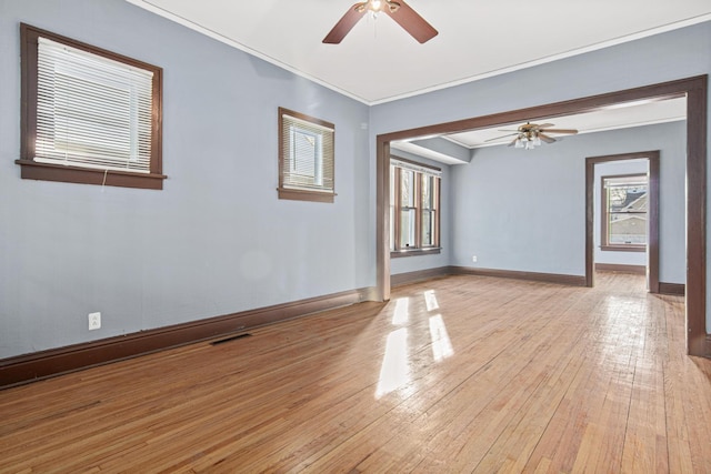 empty room with ceiling fan, ornamental molding, and light wood-type flooring