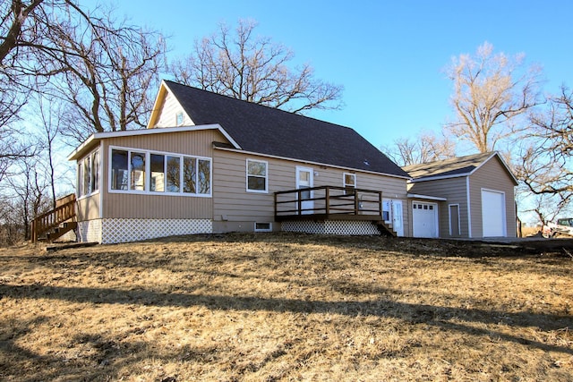 exterior space featuring a deck, a sunroom, an outdoor structure, and a detached garage