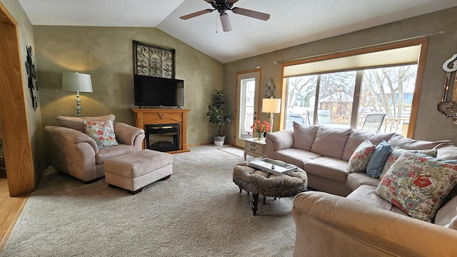 living area featuring ceiling fan, baseboards, lofted ceiling, carpet floors, and a glass covered fireplace