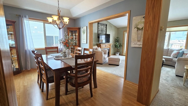 dining room with light colored carpet, a notable chandelier, a fireplace, and light wood finished floors