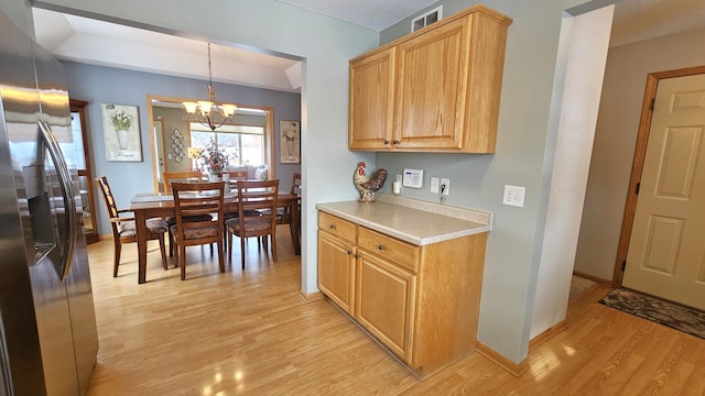 kitchen featuring light wood finished floors, stainless steel fridge, an inviting chandelier, light countertops, and baseboards