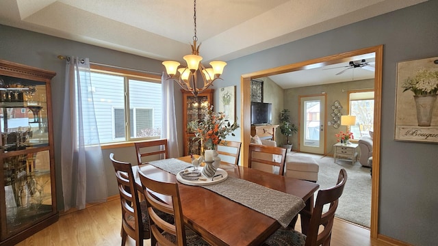 dining room with a tray ceiling, a notable chandelier, baseboards, and light wood finished floors