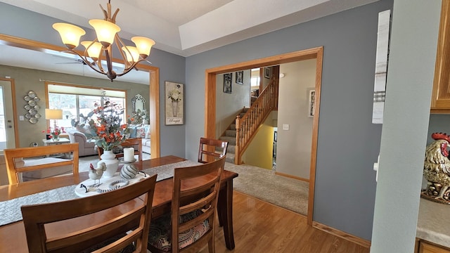 dining room with a notable chandelier, baseboards, light wood-style floors, and stairs