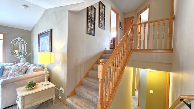 staircase featuring vaulted ceiling, carpet flooring, a healthy amount of sunlight, and baseboards