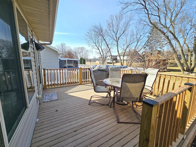 wooden deck featuring outdoor dining space, a trampoline, and fence