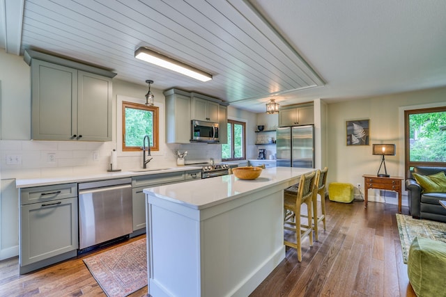 kitchen featuring a kitchen island, appliances with stainless steel finishes, wood-type flooring, sink, and gray cabinetry