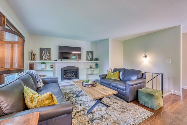 living room with hardwood / wood-style flooring and a brick fireplace