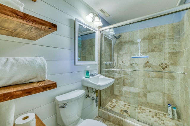 bathroom featuring sink, wooden walls, toilet, and walk in shower