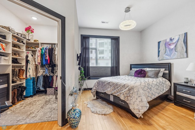 bedroom with a spacious closet, hardwood / wood-style floors, and a closet