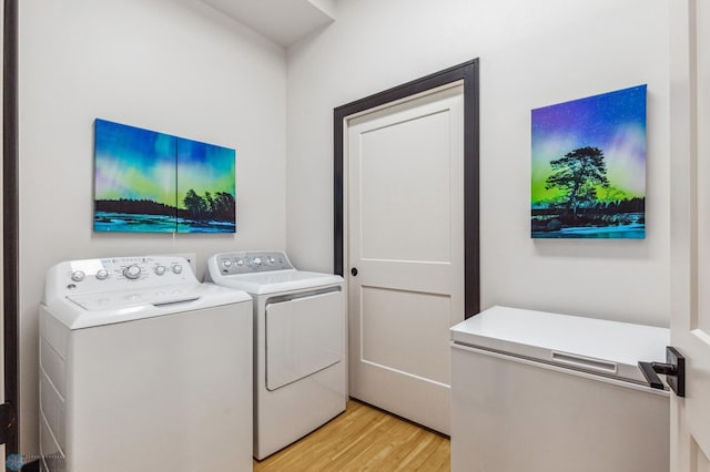 clothes washing area featuring washing machine and dryer and light wood-type flooring