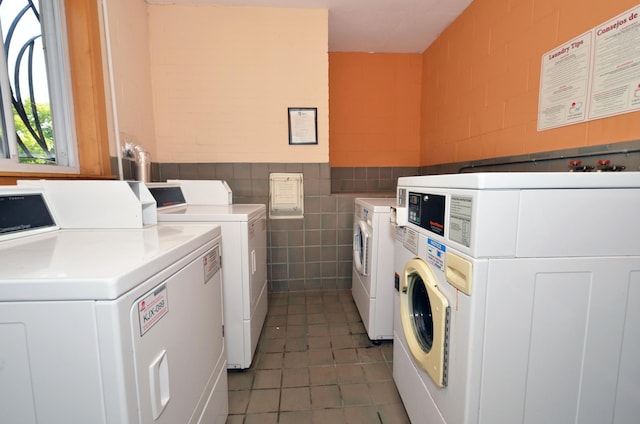 clothes washing area featuring washing machine and dryer, tile walls, and dark tile patterned floors