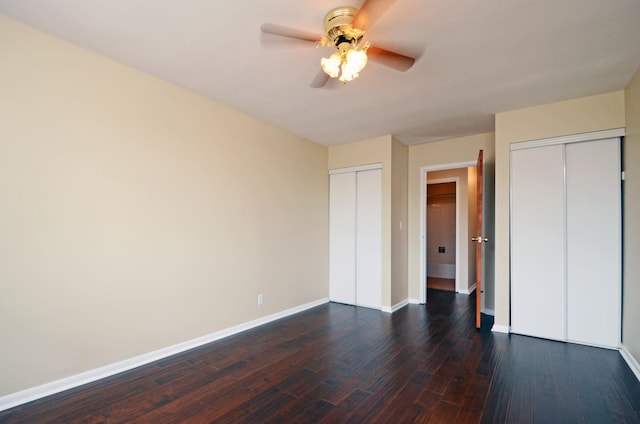 unfurnished bedroom with multiple closets, ceiling fan, and dark hardwood / wood-style floors