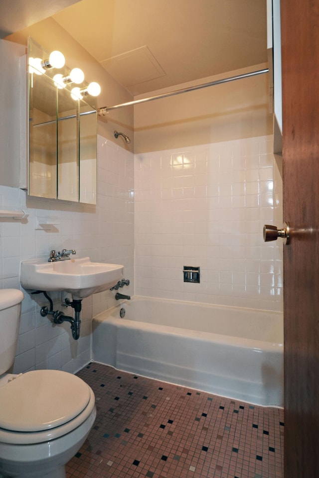 full bathroom with sink, tile walls, tiled shower / bath combo, toilet, and tile patterned floors