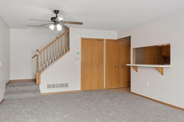 unfurnished living room with light colored carpet, a textured ceiling, and ceiling fan